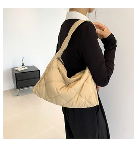 Detalle del bolso acolchado beige con silueta de media luna y correa ancha al hombro