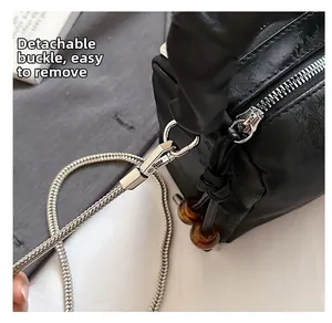 Detail of detachable silver buckle and snake chain on black pleated handbag