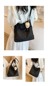 Detail of black nylon tote bag with drawstring closure and cute plush charm