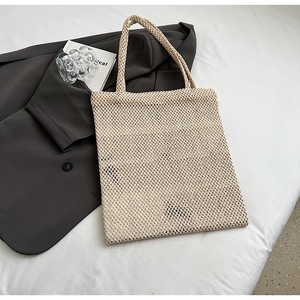Close-up of beige crochet mesh tote bag with woven texture and dual handles