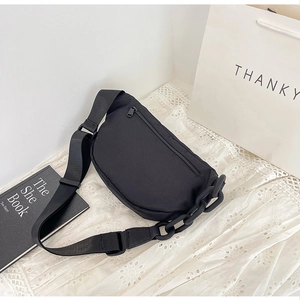 Detail of black canvas waist bag with bold chain decoration and adjustable wide strap