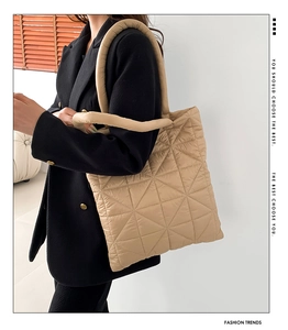 Close-up of beige quilted shoulder bag with soft padded handles and triangular patterns