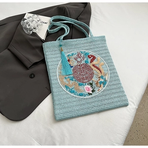 Detail of light blue straw bag with traditional Chinese dragon embroidery and silk tassel