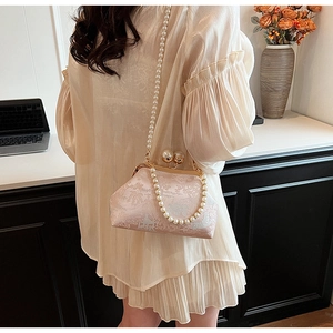 Detail of embroidered satin bag with dual pearl chains shown on a model