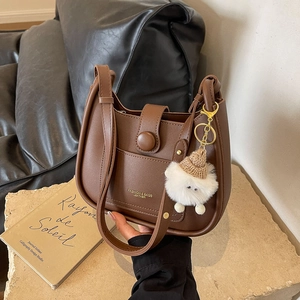 Deep brown leather hobo bucket bag with stylish contrast trim and plush charm