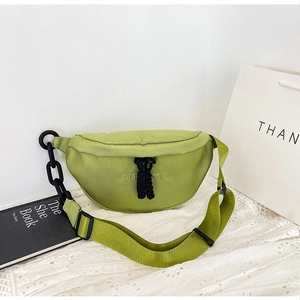 Detail view of avocado green canvas crossbody bag featuring black chain and cord accents