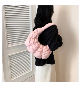 Detailed close-up of a pink pleated cloud bag worn as a shoulder accessory