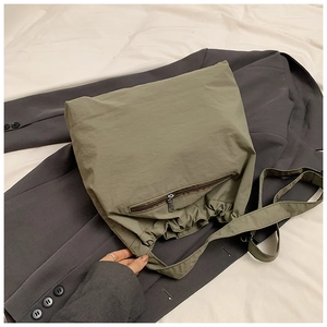 Detail of army green nylon tote bag with drawstring closure and metal zipper pocket