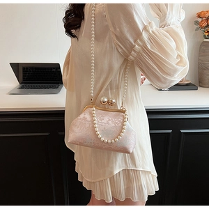 Detail of pink brocade satchel featuring pearl kiss-lock and elegant beaded chain