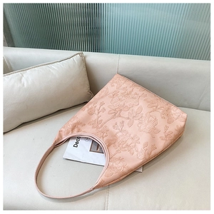 Close-up of pink hobo bag with embossed 3D rose floral texture on leather surface
