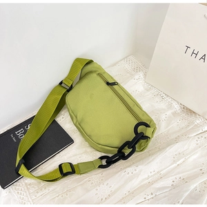Close-up of lime green nylon crossbody bag featuring a chunky black plastic chain detail