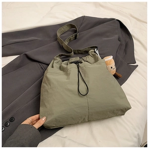 Detail of army green nylon drawstring tote bag with cute coffee cup plush charm accessory