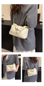 Detail of creamy pleated cloud bag showing PU texture, metal chain, and soft handle