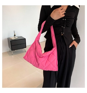 Primer plano de un bolso de hombro de nailon acolchado rosa llevado por una modelo