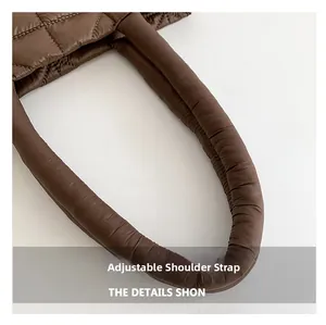 Detail of adjustable padded shoulder strap on a brown quilted nylon shoulder bag