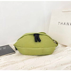 Detail of green canvas crossbody bag with CLEAN logo and black knotted zipper pull