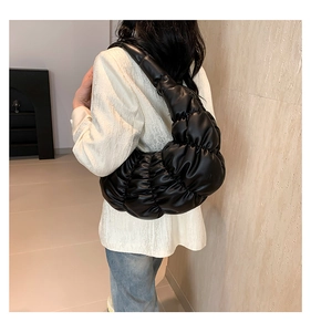 Detail of black pleated cloud bag texture and shoulder fit on female model