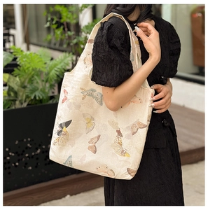 Close-up of minimalist canvas tote bag with vibrant butterfly print in an outdoor setting