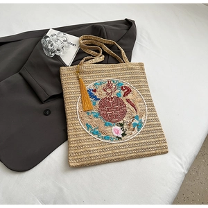 Detail of traditional Chinese dragon and phoenix embroidery with silk tassel on straw bag