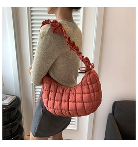Detail van gewatteerde hobo-tas in oranje met ruches aan de riem en een strik opzij