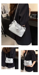 Detail of silver pleated handle handbag with chain strap shown with black suit