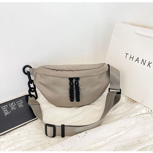 Detail of beige nylon half-moon waist bag with black chain and woven zipper pullers