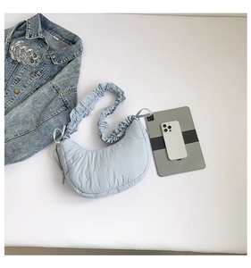 Detail of light blue crescent shoulder bag with pleated strap and side ribbon bow decor