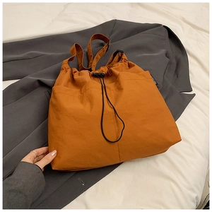Detail of caramel nylon tote bag showing drawstring closure and durable fabric texture