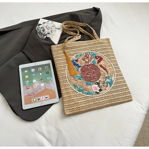 Detail of straw tote bag with Chinese embroidery, tassel charm and spacious interior