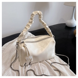 Close-up of cream ruched handle handbag with dual zippers and silver chain detail