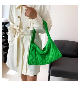 Detalle de bolso tote acolchado verde brillante con diseño de rombos y gabardina blanca