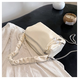 Detail of ruched handle and silver chain on creamy faux leather rectangular handbag