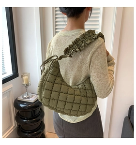 Detailed view of olive green quilted dumpling bag with stylish ruffled shoulder strap