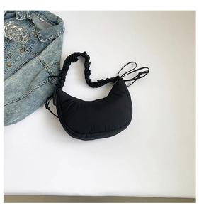 Detail view of black crescent shoulder bag featuring ruched handle and side drawstring