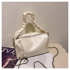 Detail of beige pleated satin handbag with a sleek metal chain and vogue aesthetic design