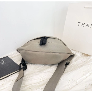 Close-up of khaki canvas crossbody bag with woven texture and black rope zipper pulls