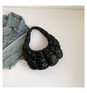 Detail of black pleated cloud bag with soft PU texture styled with a denim jacket