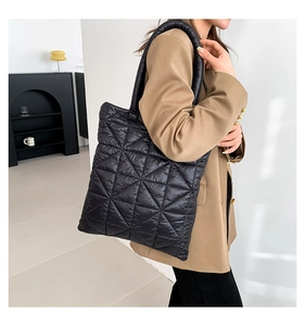 Model showing a black quilted down tote bag with a geometric triangle pattern design