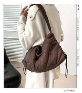 Detail der dunkelbraunen gesteppten Puffer-Schultertasche mit Kordelzug und breitem Riemen