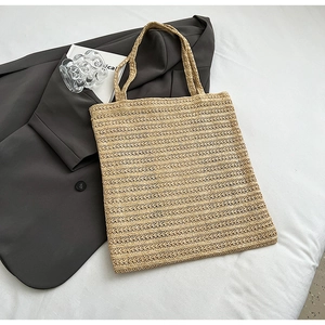 Detail of hand-woven straw tote bag with horizontal texture on a clean white background