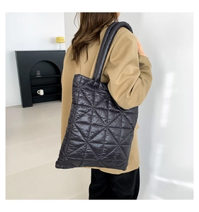 Close-up of black quilted tote bag with triangle stitching and padded wide shoulder strap