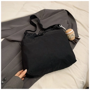 Close-up of black nylon tote bag with drawstring closure and cute plush cup charm