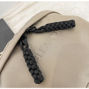 Detail of khaki oxford cloth sling bag featuring dual zippers with black woven cord pulls