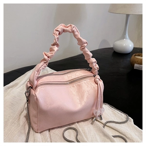 Close-up of pink pleated satin handbag with dual zippers and silver chain detail