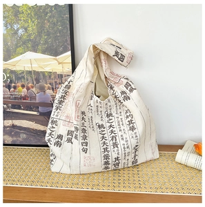 Detail of canvas knot bag featuring Chinese calligraphy and red seal on textured mat