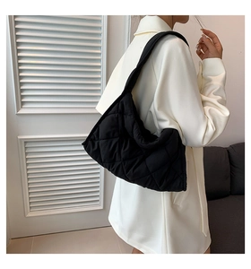 Vista lateral de un bolso tote negro acolchado en modelo mostrando capacidad y textura