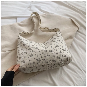 Détail du sac hobo à fleurs violettes avec un tissu texturé de couleur blanc cassé