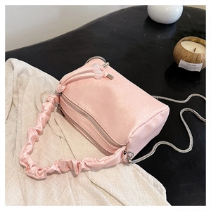 Detail of pink satin pleated handbag with dual zippers and silver chain strap