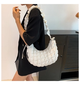 Side view of a quilted white hobo bag with ruffled straps worn by a female model