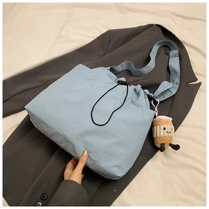 Detail of light blue nylon tote bag with drawstring closure and cute plush charm